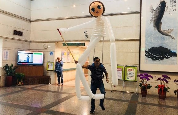 繼仁主任背起大偶，練習操作，正在適應如何讓氣球大偶順利的活動。