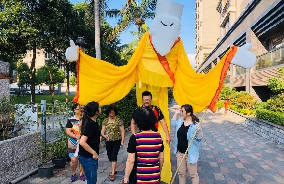 在有德老師示範之後，里長第一次著裝，大家協助里長操作大偶的手。